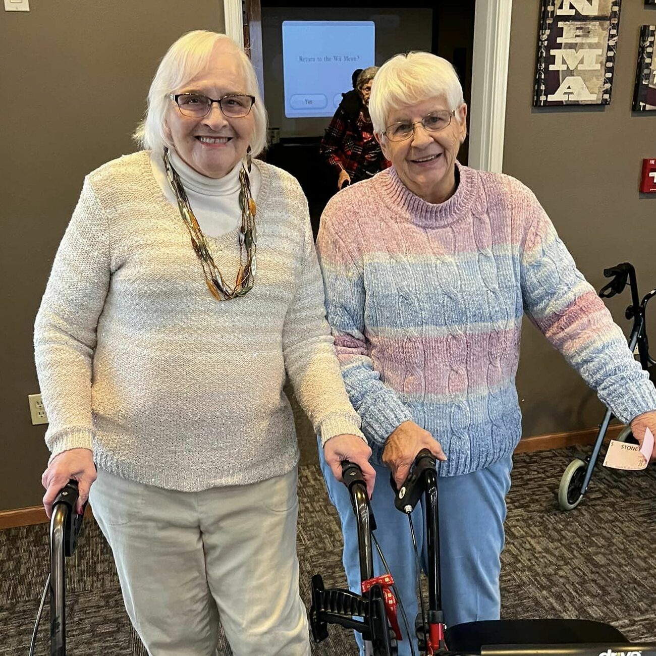 Two senior women smiling together indoors.
