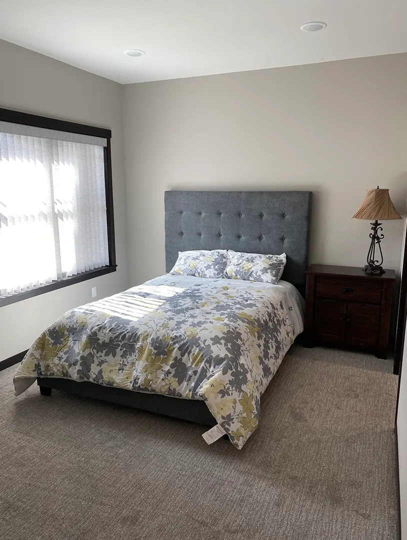 Cozy bedroom with floral bedding and bedside lamp.