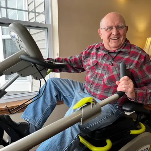 Elderly man using fitness equipment indoors.