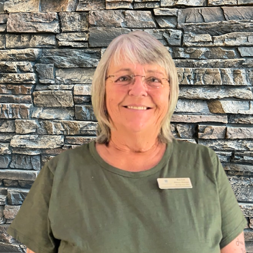 Smiling staff member in front of a stone wall.