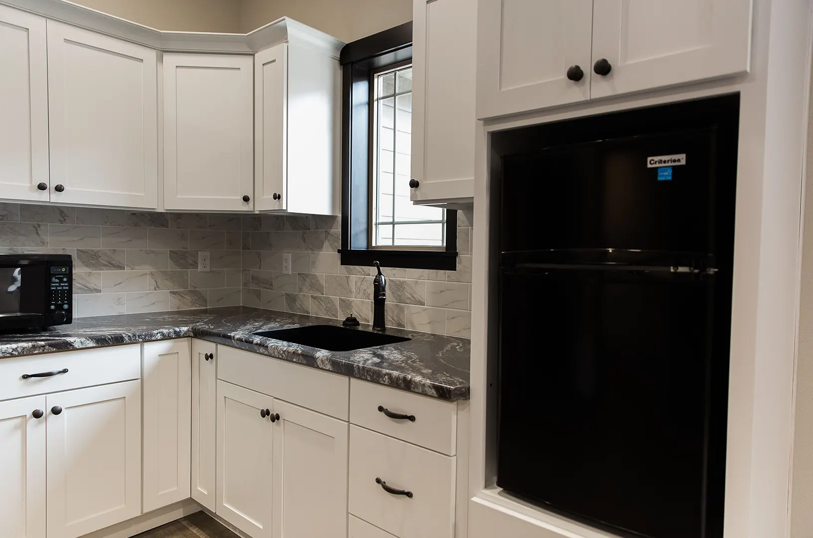 Modern kitchen with white cabinets and black appliances.