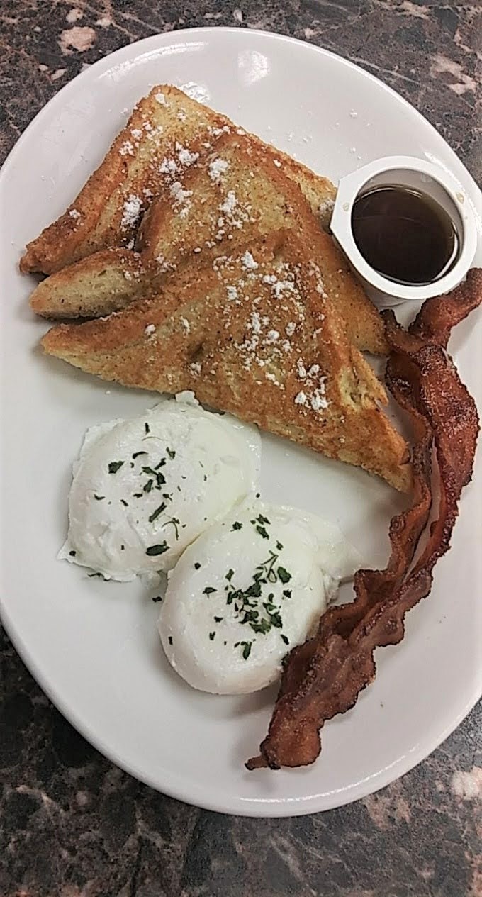 A plate of French toast, eggs, and bacon.
