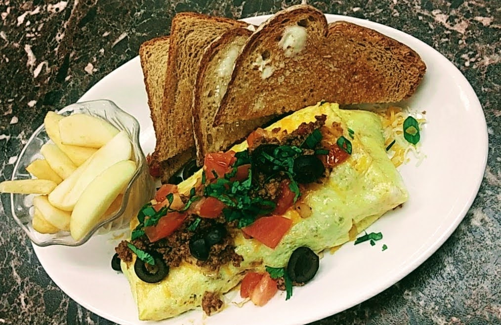 A plate of food with omelette, toast, and apples