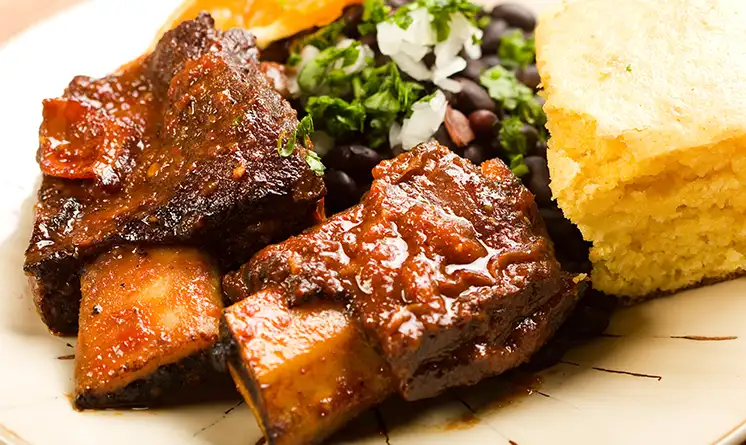 Plate of food featuring beef, beans, and cornbread