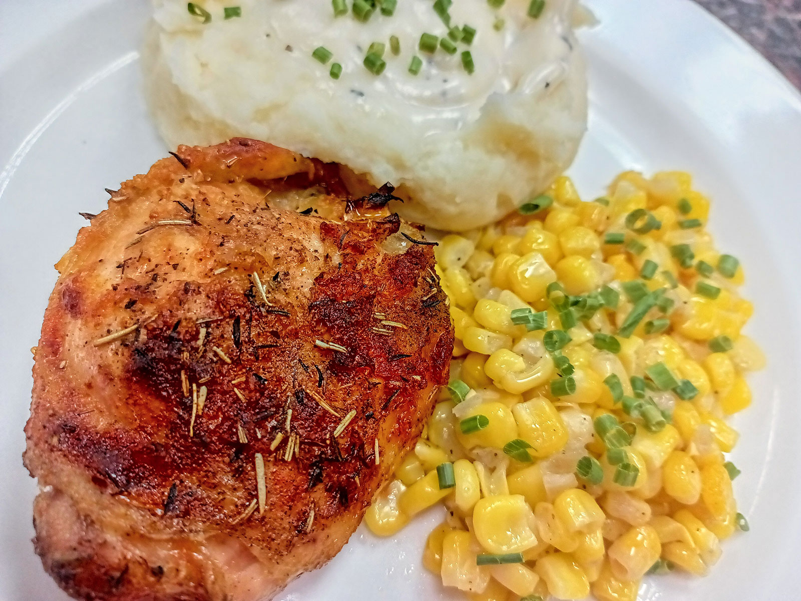 Plate of grilled chicken, mashed potatoes, and corn