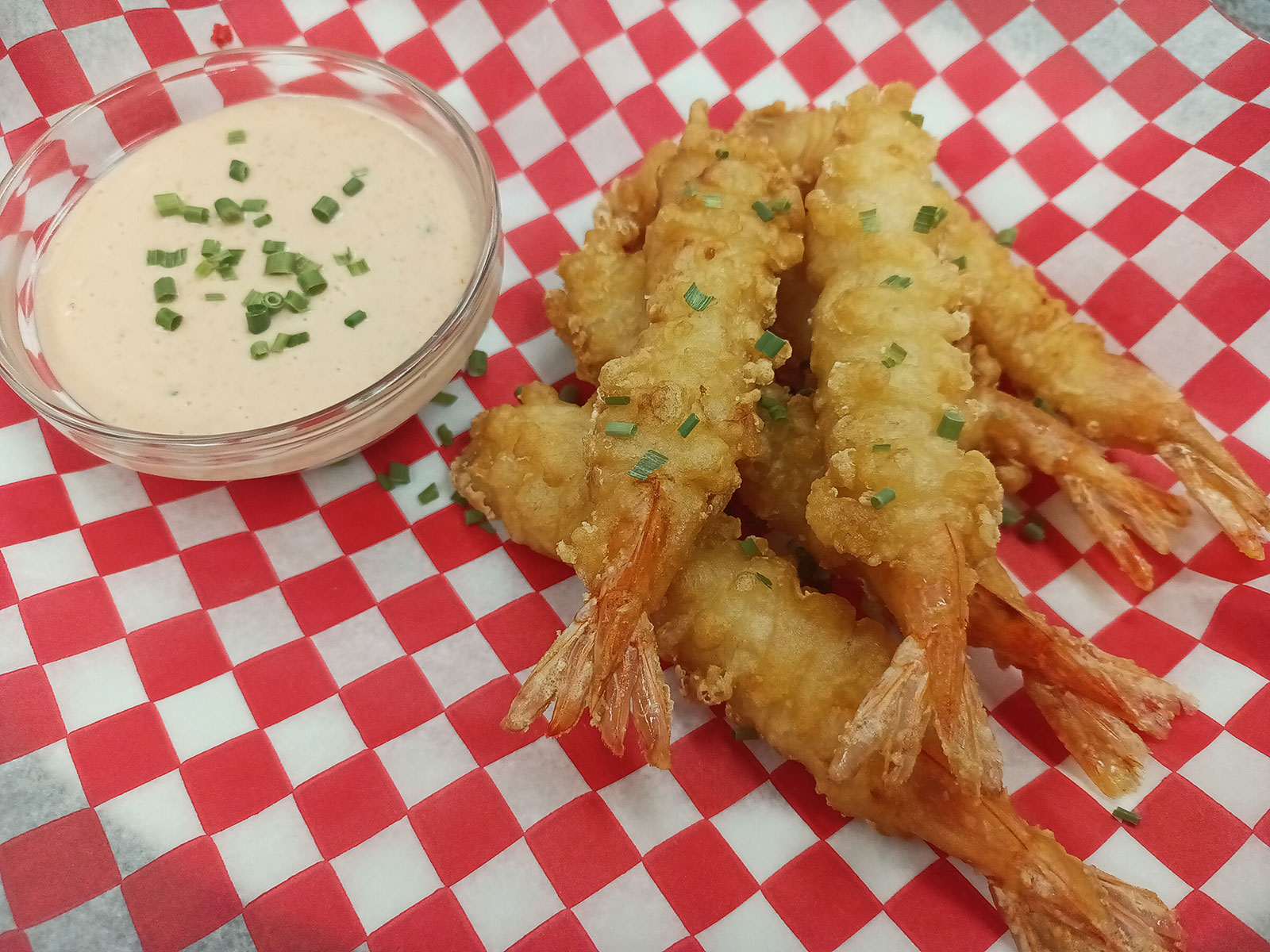 Fried shrimp with dipping sauce on a checkered plate