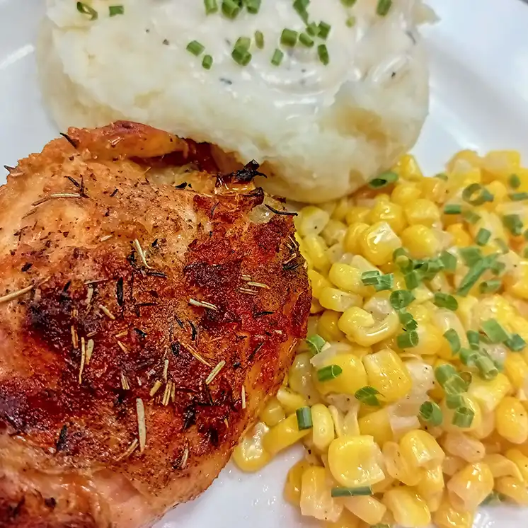 Plate of roasted chicken, mashed potatoes, and corn