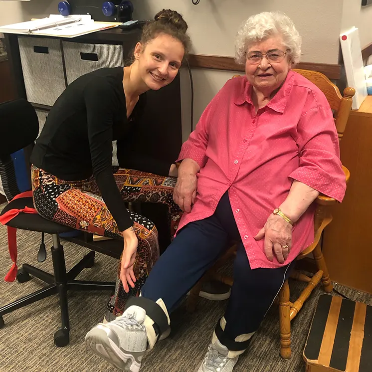 Staff member assisting senior resident with exercises.
