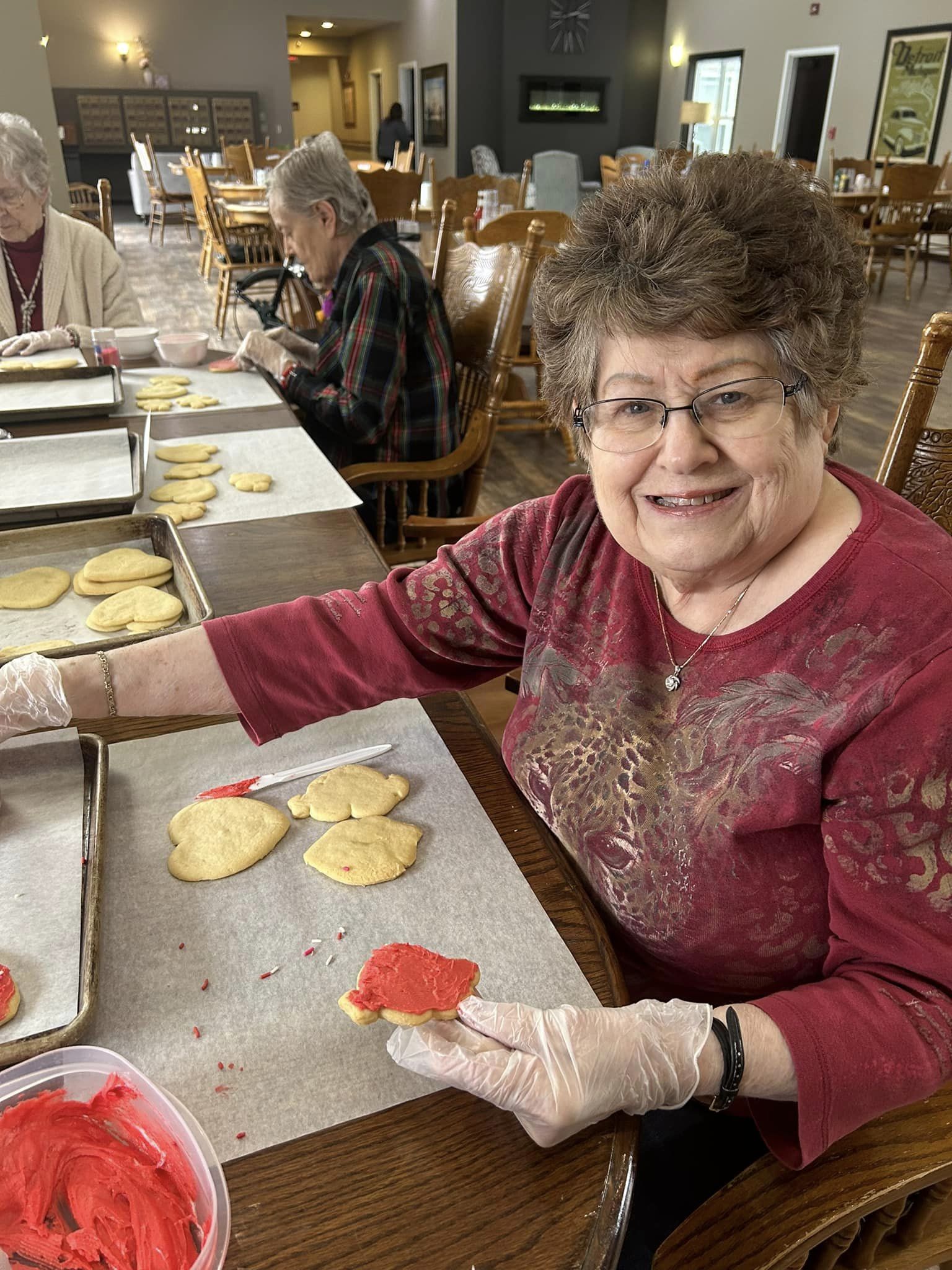 Senior resident decorating cookies in a common area.