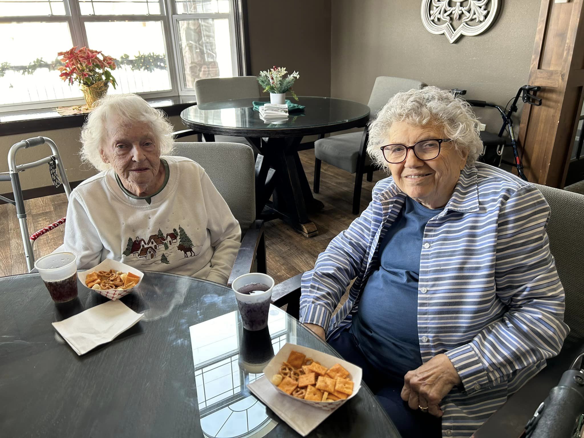 Two smiling residents enjoying snacks in a common area.