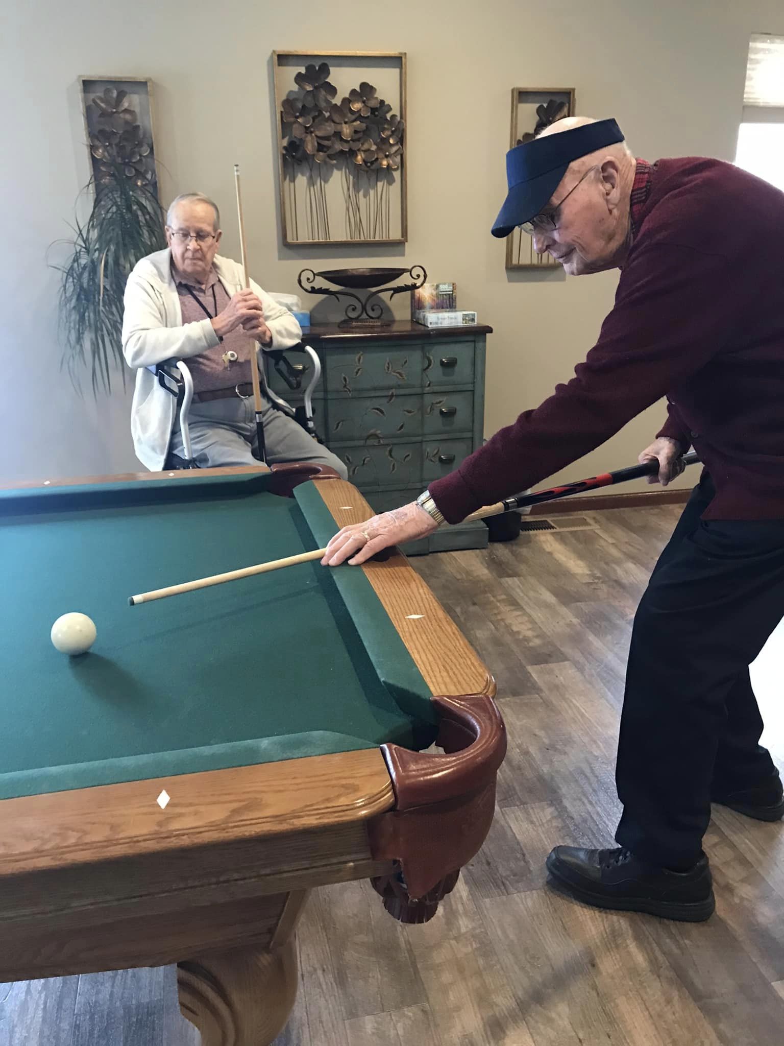Two seniors playing pool in a common area.