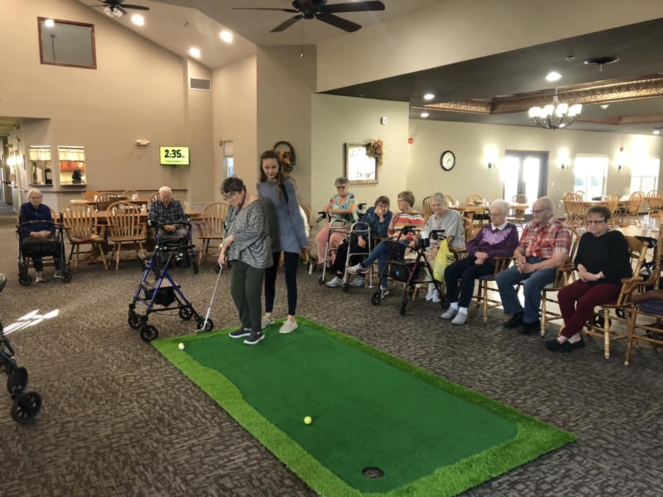 Residents participating in indoor mini-golf activity.