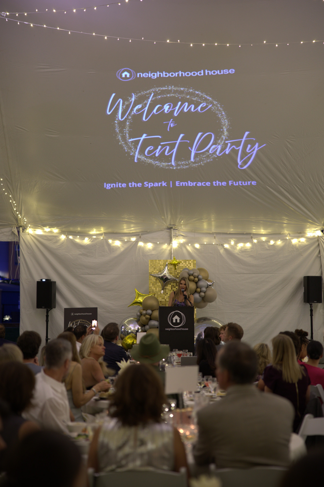 People gathered at a festive event under a tent.