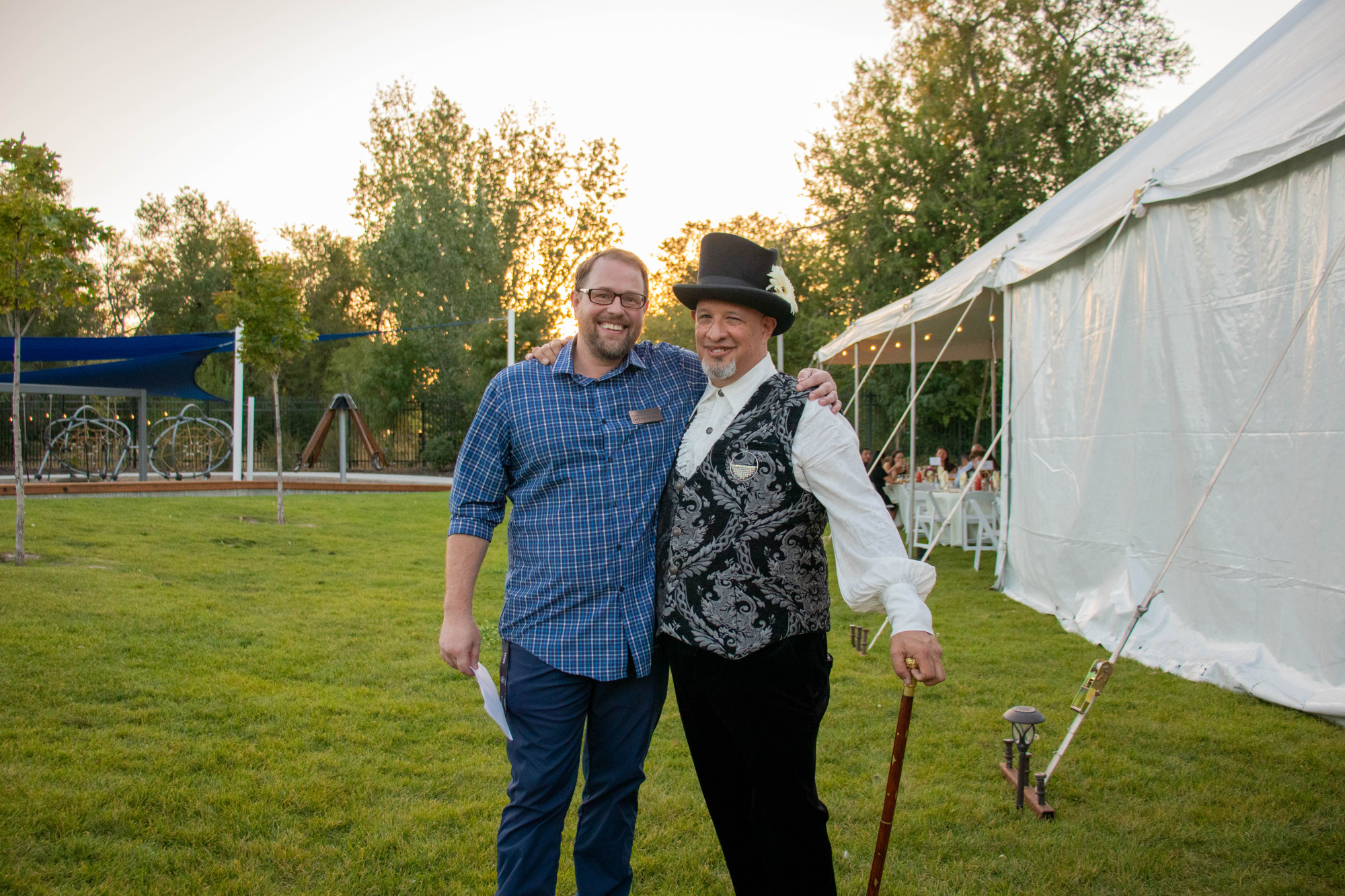 Two men smiling outdoors at an event.