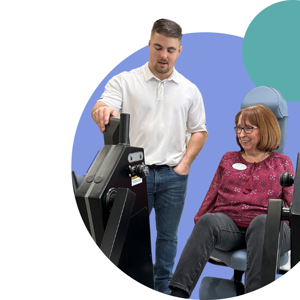 Staff assisting a resident with fitness equipment.