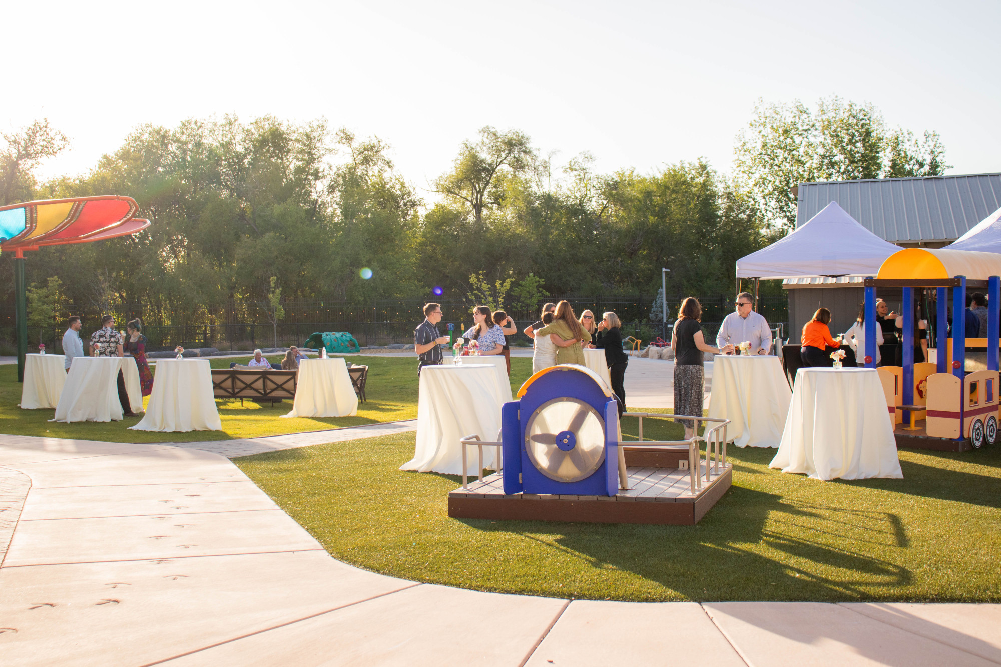 Outdoor gathering with people and tables set up.