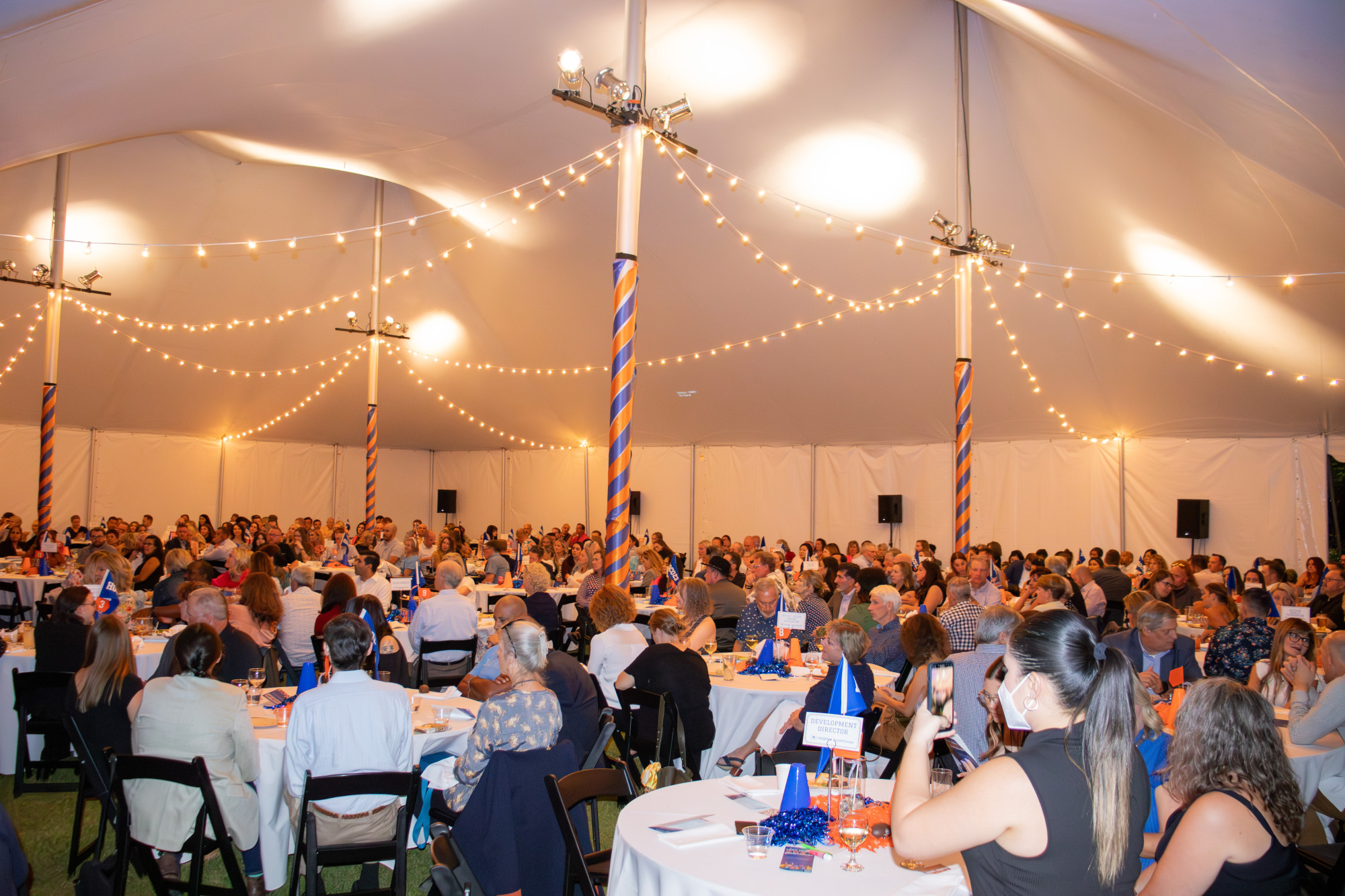 Crowded event tent with people and decorations.