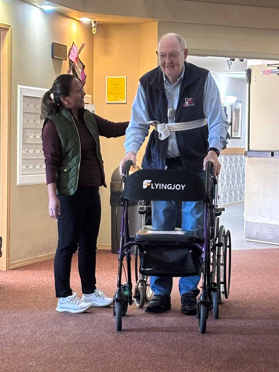 Staff assisting resident in a facility hallway