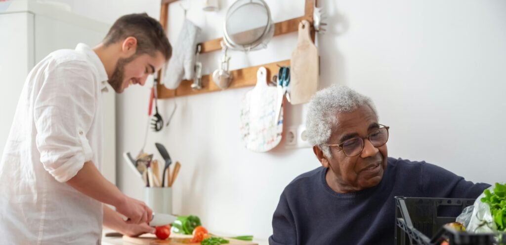 Resident and staff member preparing food together.