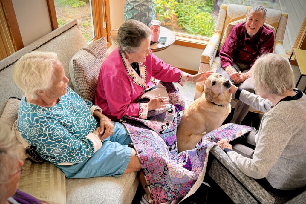 Residents interacting and petting a dog in a common area.