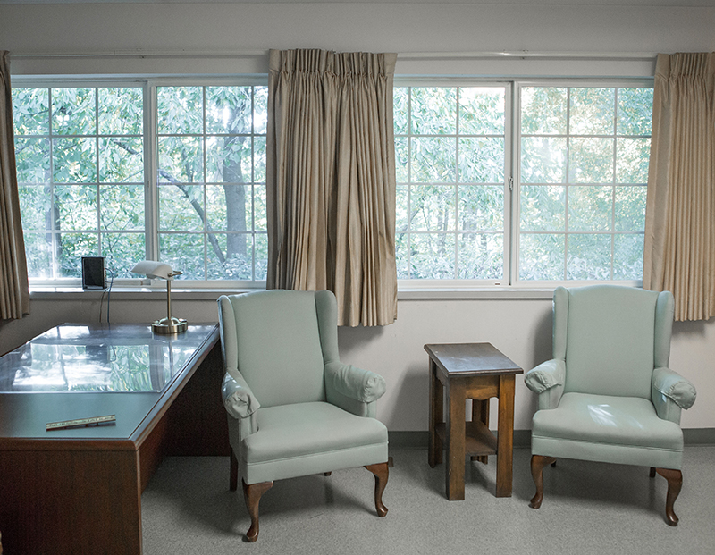 Common area with chairs and a desk by the window.
