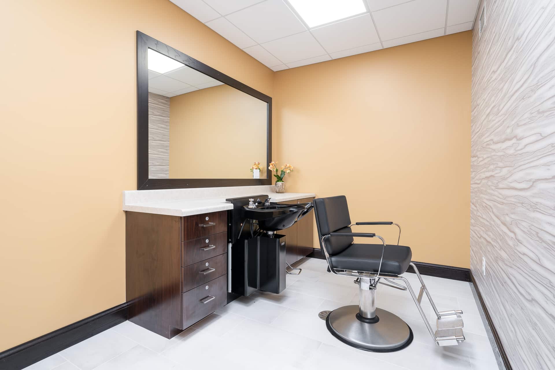 Beauty salon area with a chair and mirror.