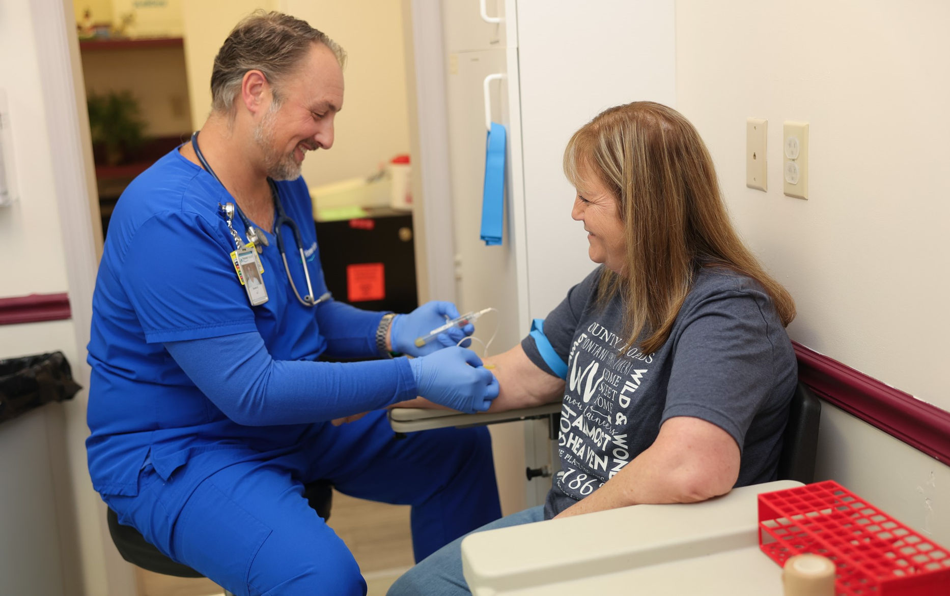 Nurse assisting a resident with a medical procedure.