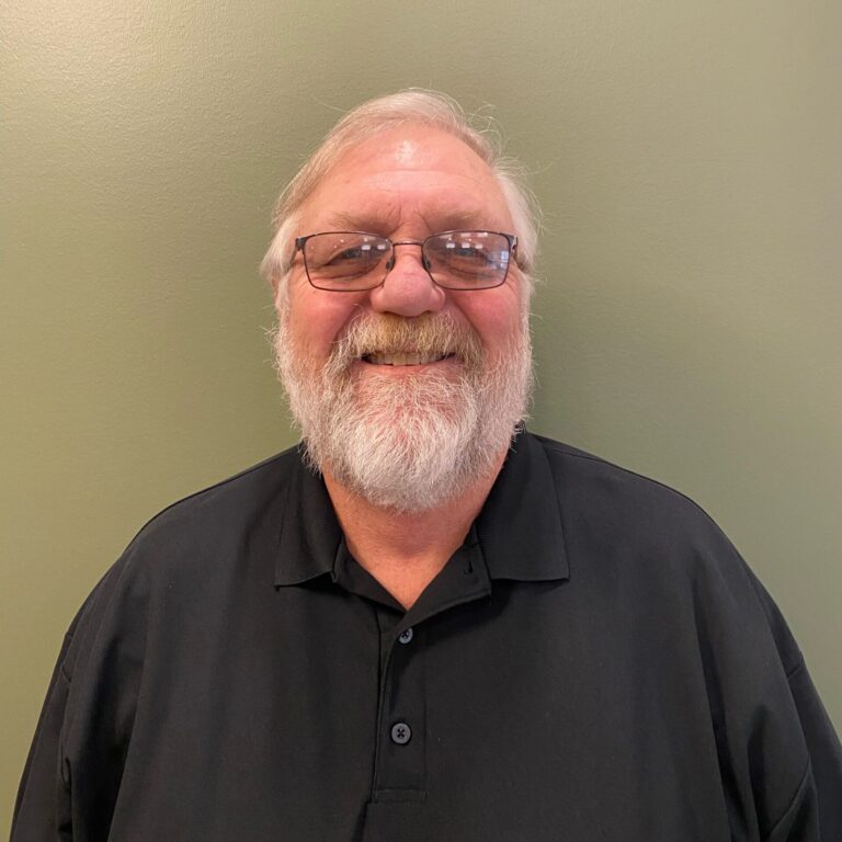 Smiling elderly man with glasses, dark polo shirt