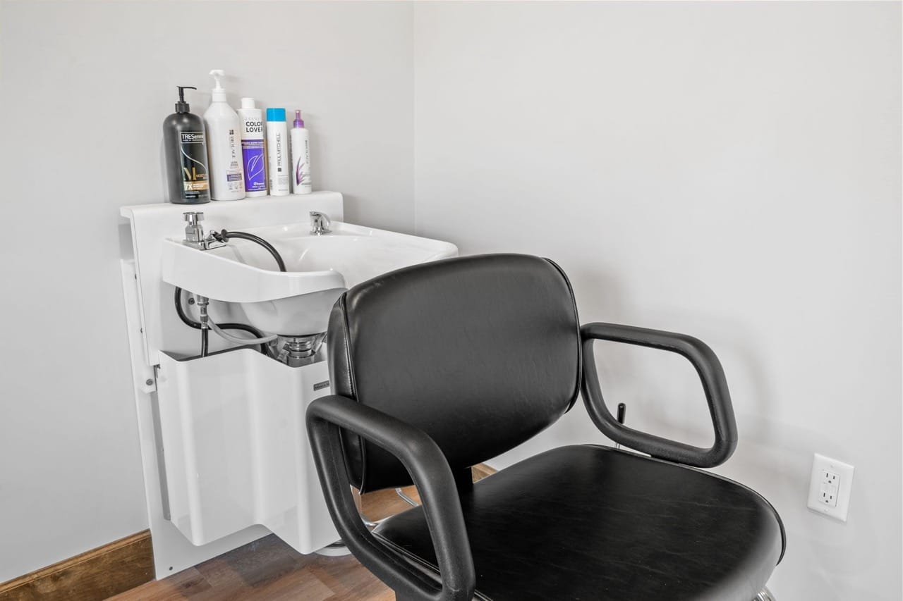 A hair salon chair and sink in a room.