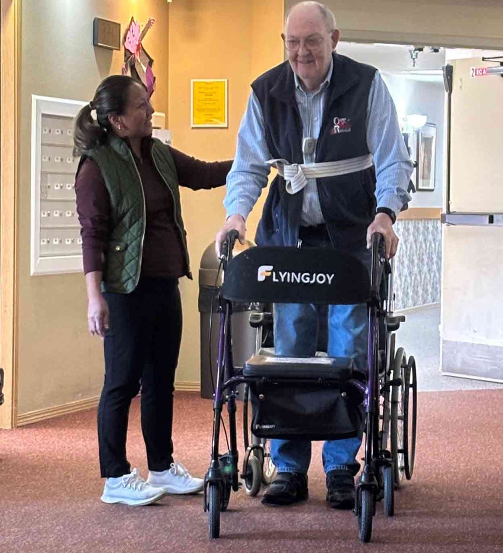 Staff assisting a resident with a walker.