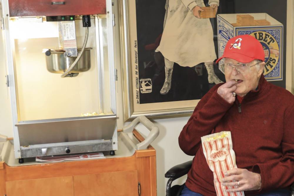 Resident enjoying popcorn at a popcorn machine.