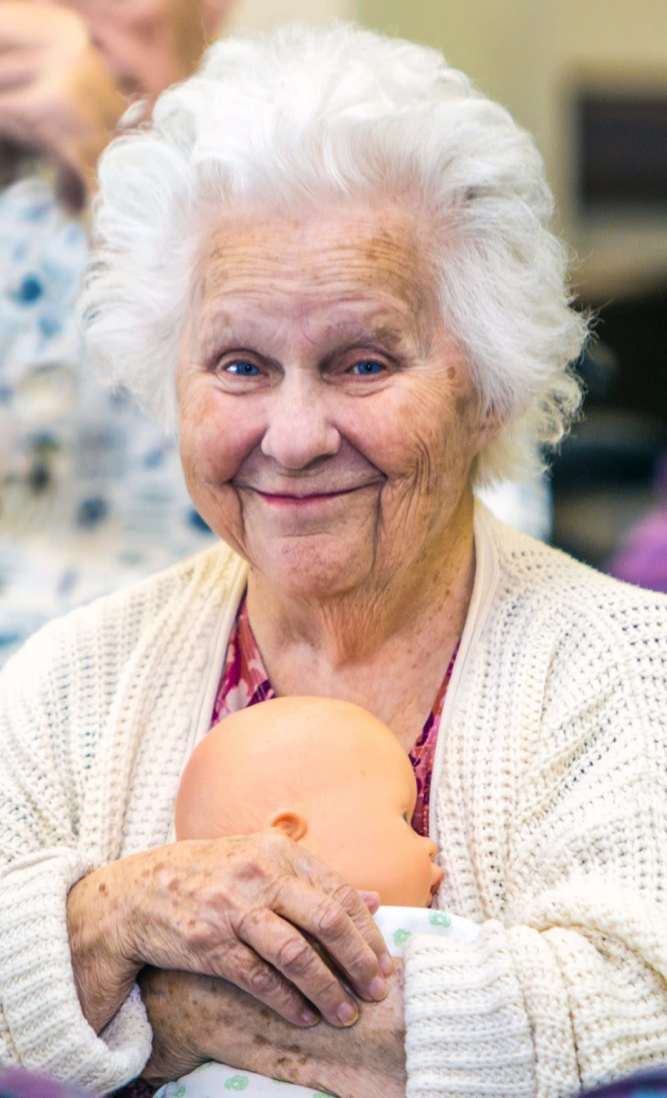 Smiling elderly woman holding a baby doll