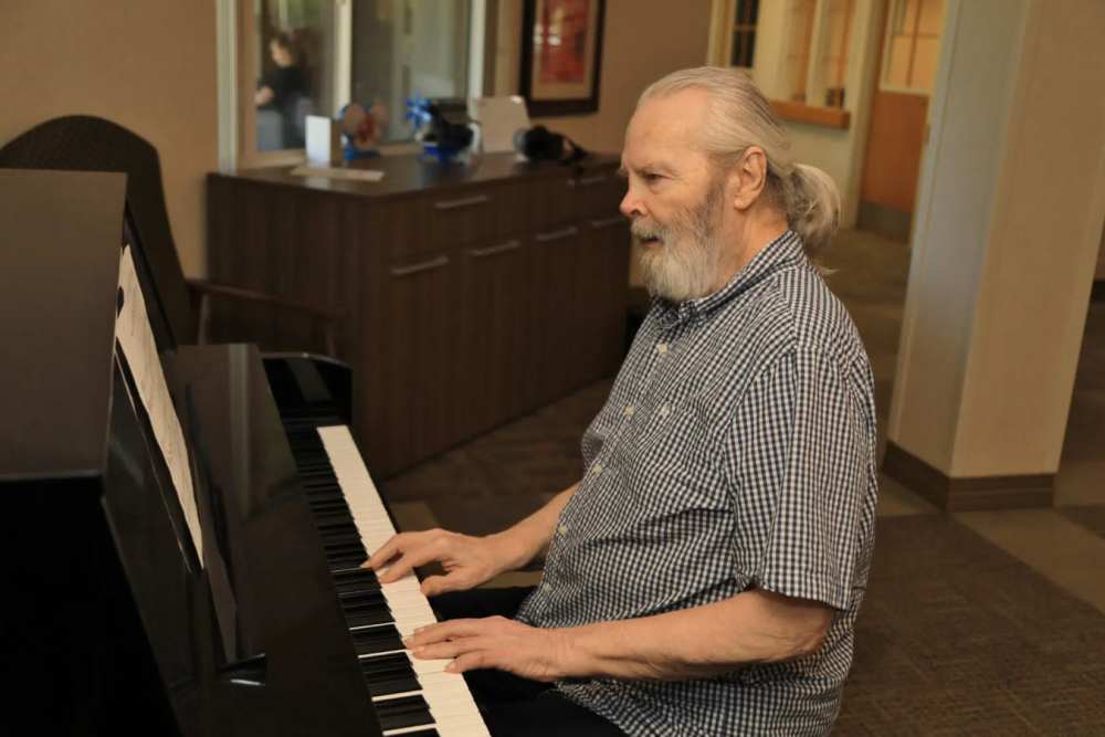 Elderly man playing piano in a common area