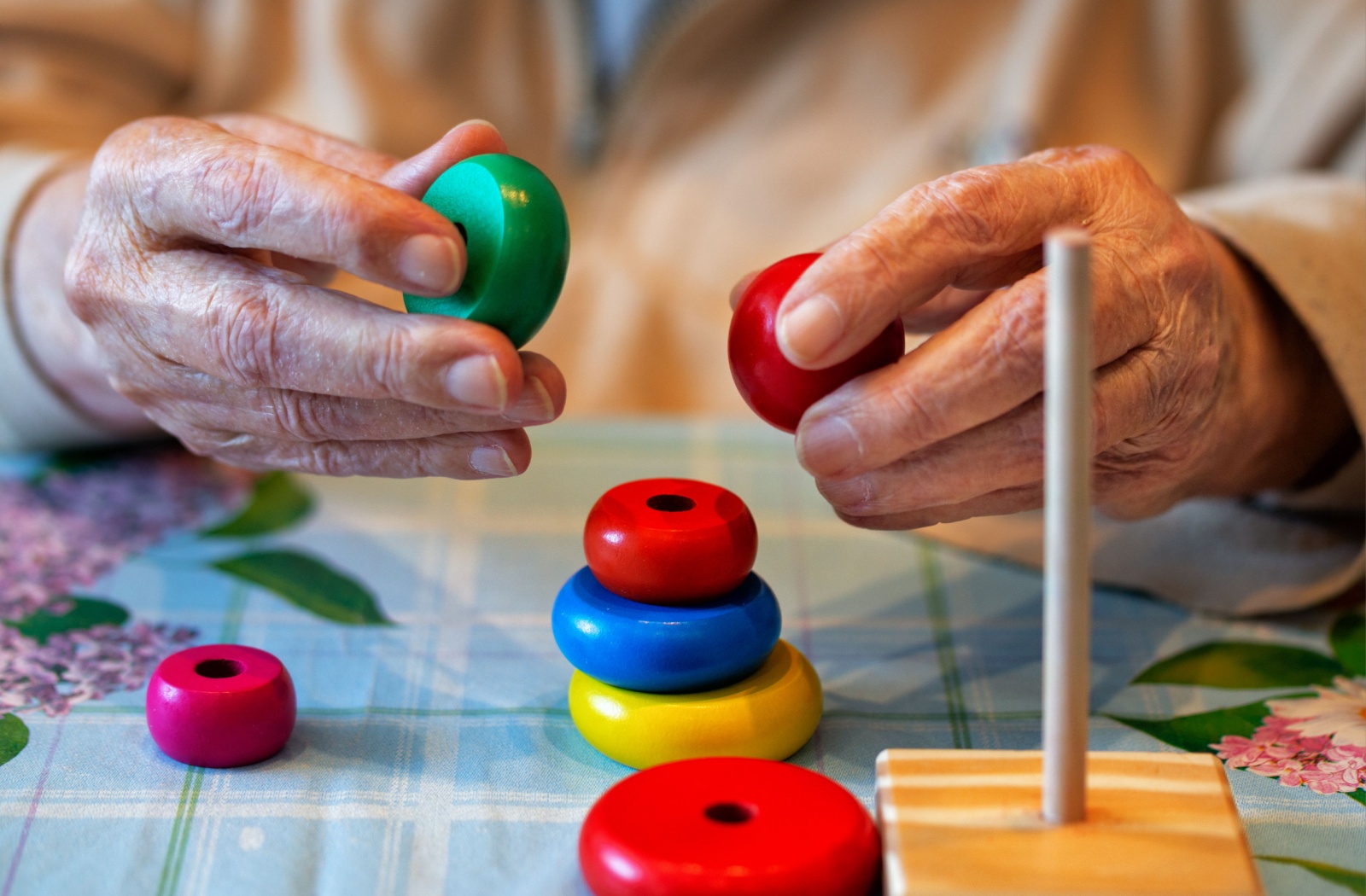 Hands of a resident playing with colorful stacking rings.