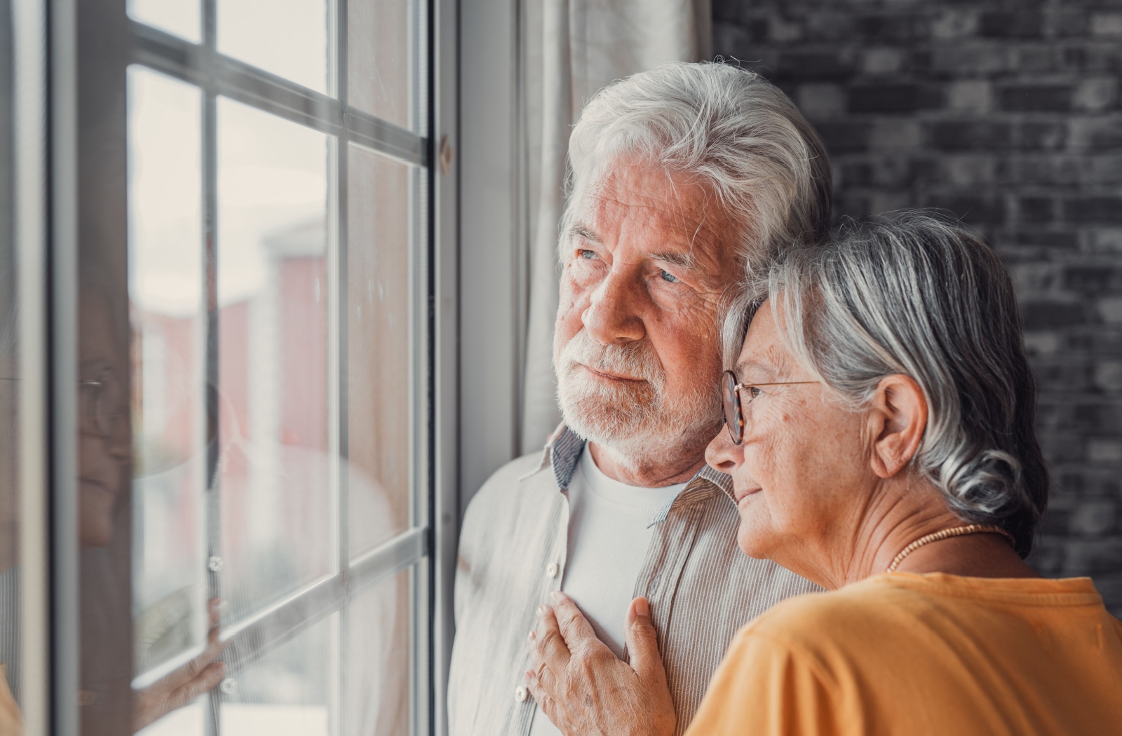 Elderly couple embracing by a window