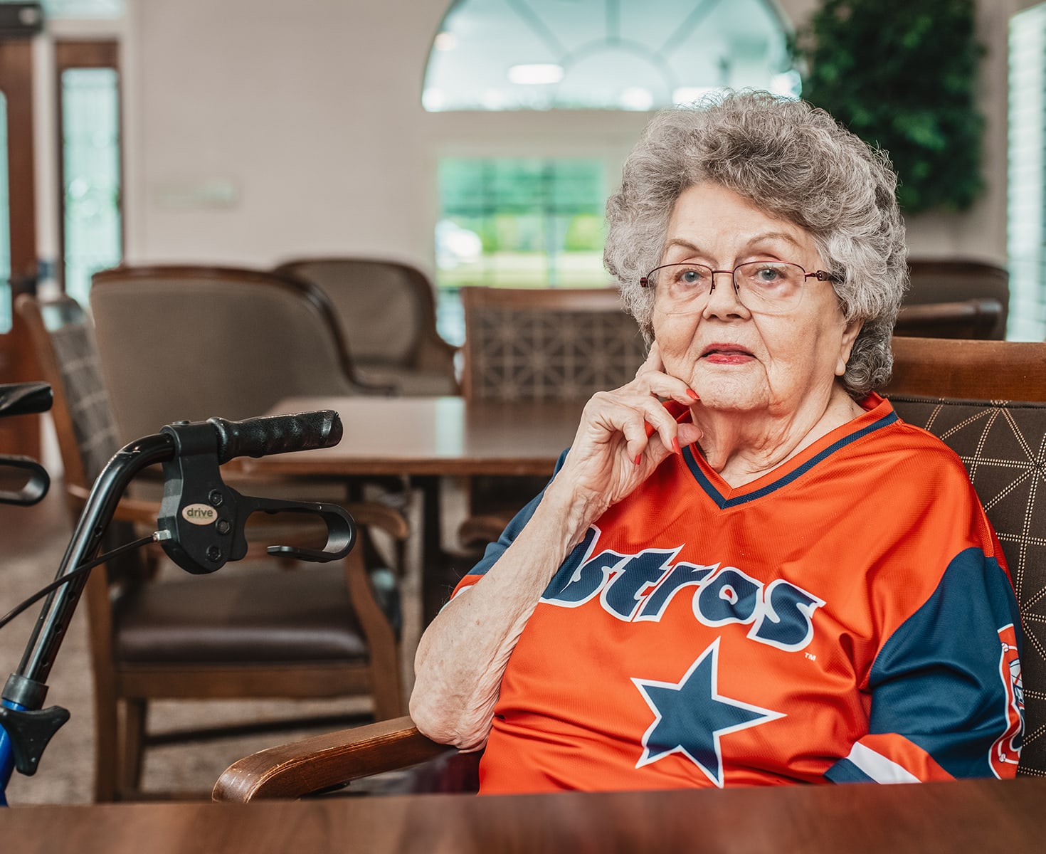 Elderly woman in Astros jersey sitting in lounge