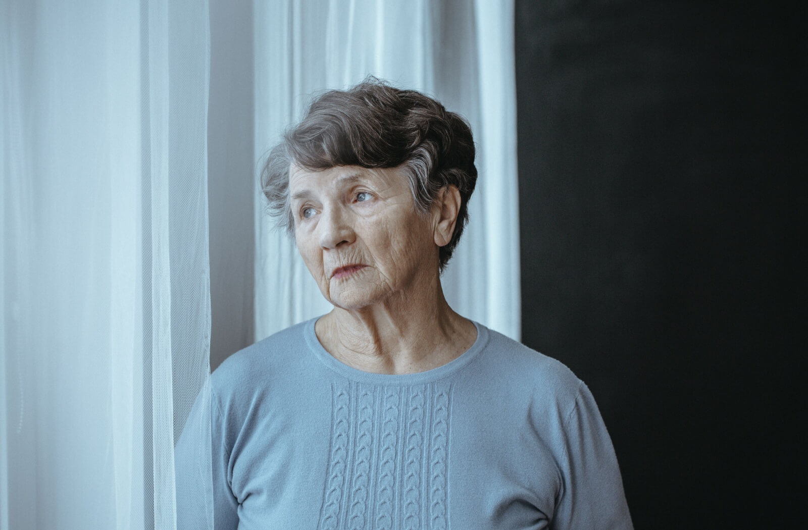 Senior woman gazing thoughtfully out the window.