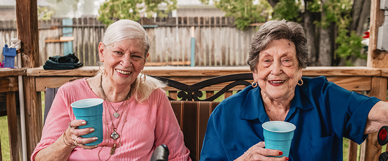 Two happy residents enjoying drinks outdoors