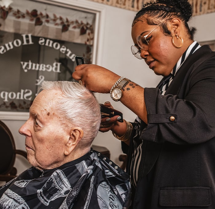Hair stylist giving a haircut to an elderly man.
