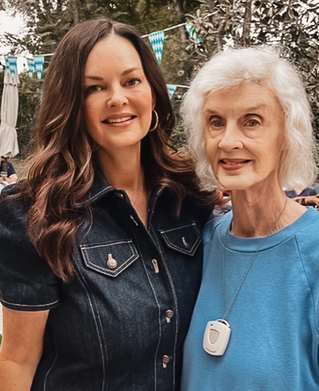 Two women posing outdoors, smiling happily.