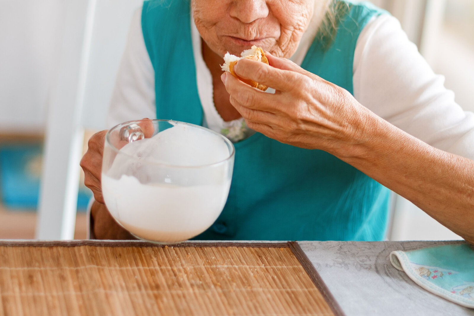 Senior woman enjoying food at a dining table.