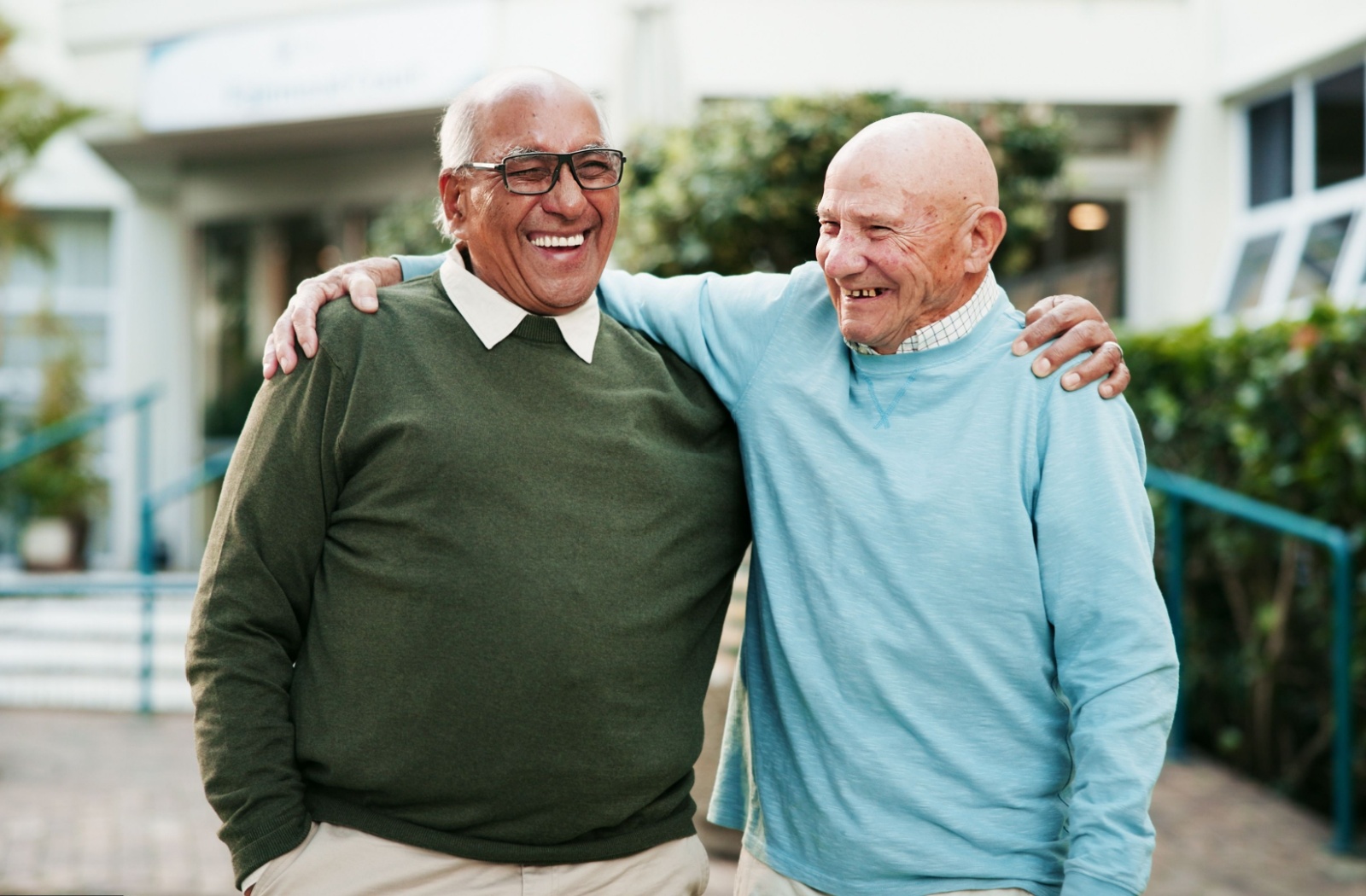 Two elderly men laughing together outdoors.