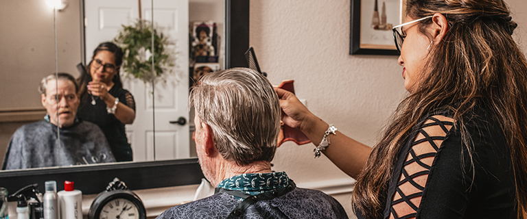 Resident receiving a haircut in a salon setting.