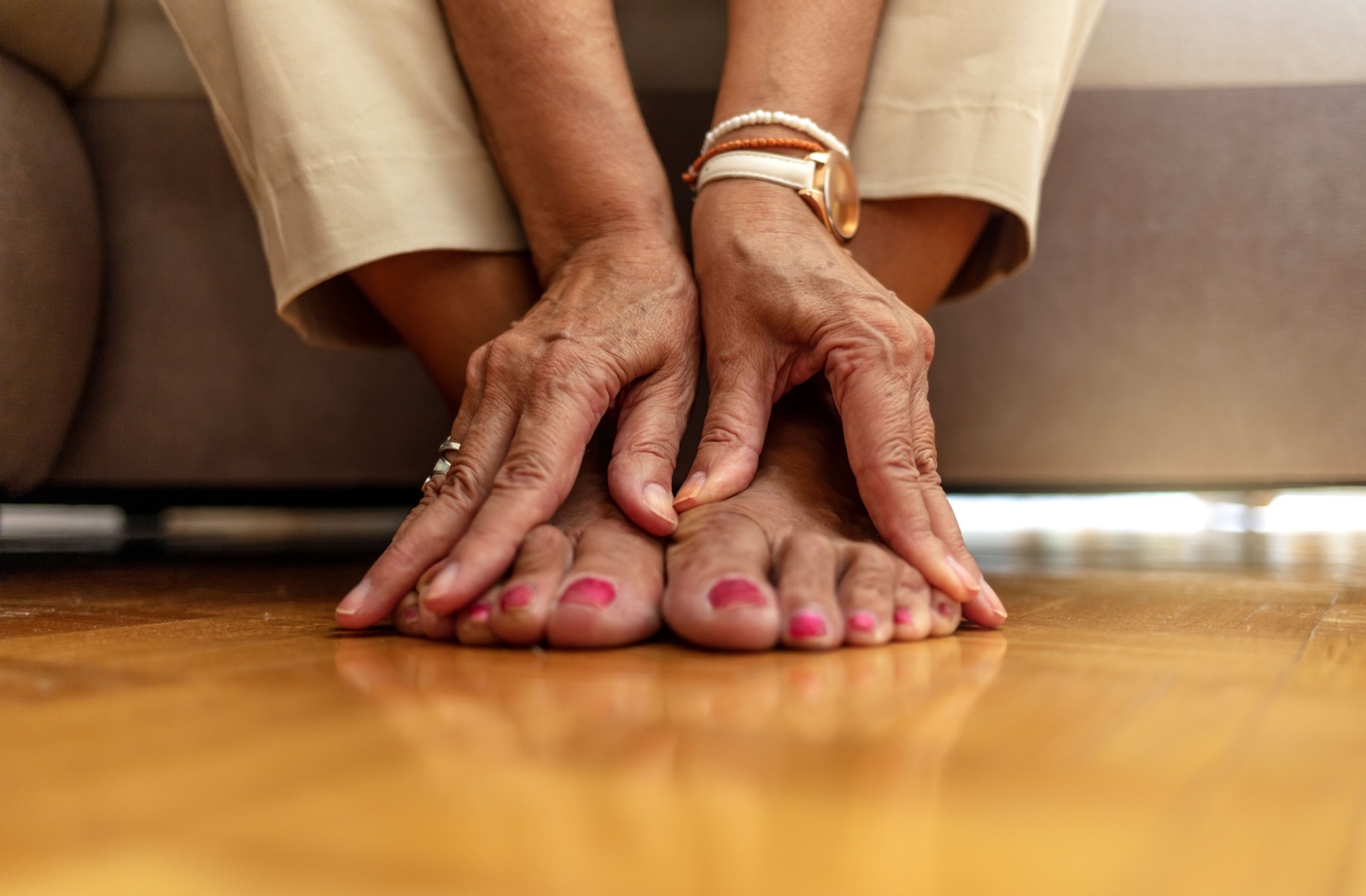 Close-up of hands and feet on a wooden floor.