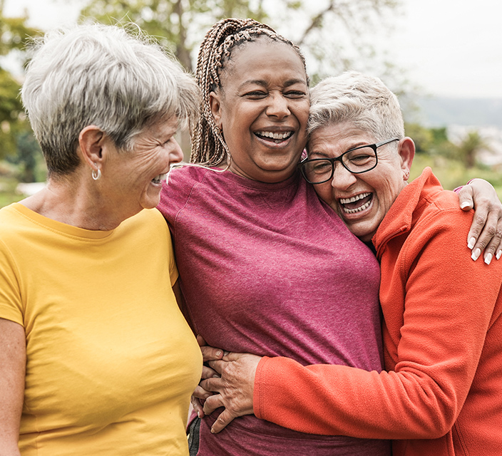 Three women laughing together outdoors