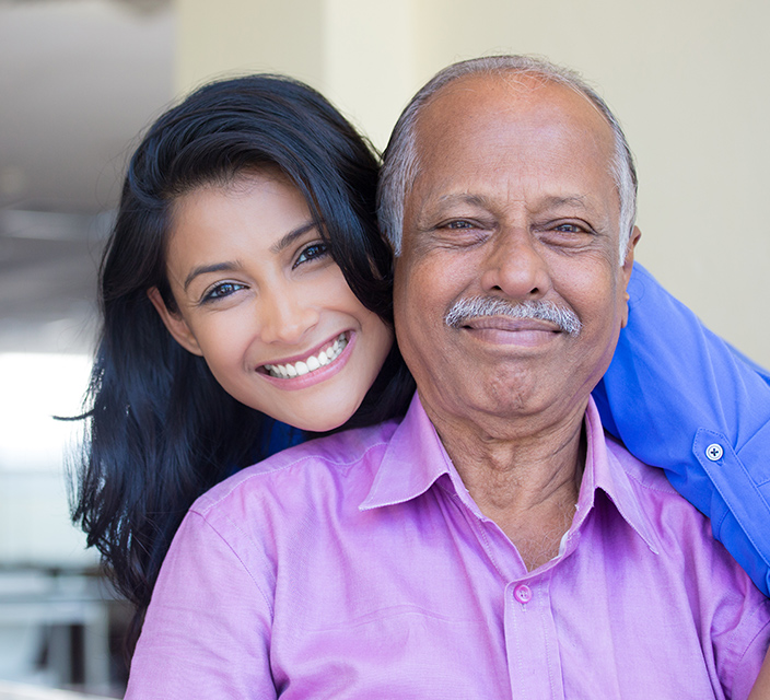Smiling woman embracing elderly man indoors