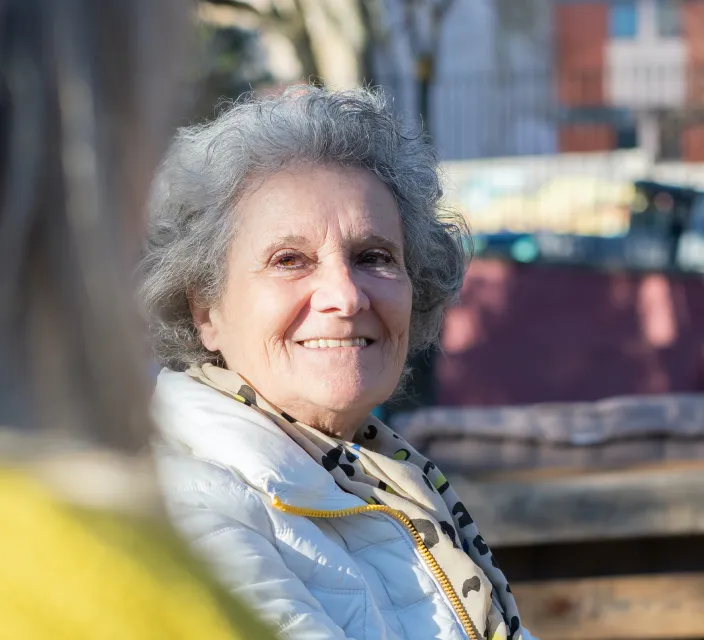Smiling elderly woman enjoying outdoor space.