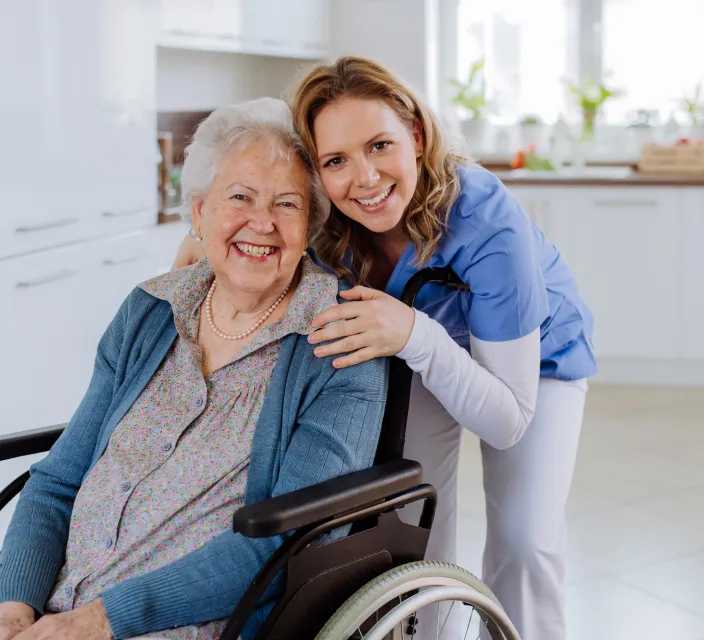 Senior resident smiling with a caregiver in a kitchen