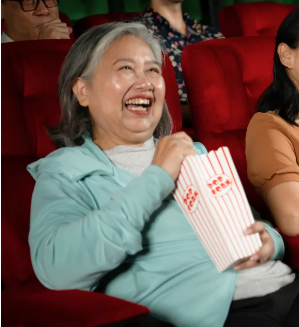 Senior woman enjoying popcorn in a theater
