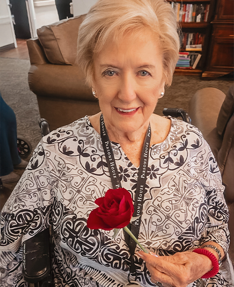 Senior resident smiling with a rose in hand